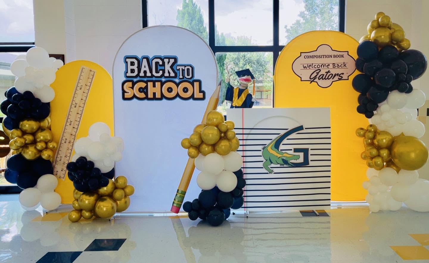 Back to School branded panels with navy, gold and white balloon columns and school mascot details