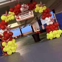 Red and yellow balloon arch entrance with branded banner