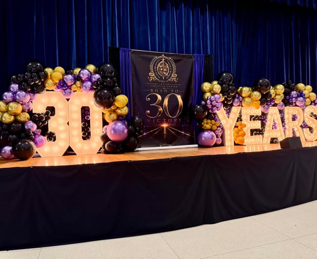 30-year anniversary stage with gold marquee numbers and balloons