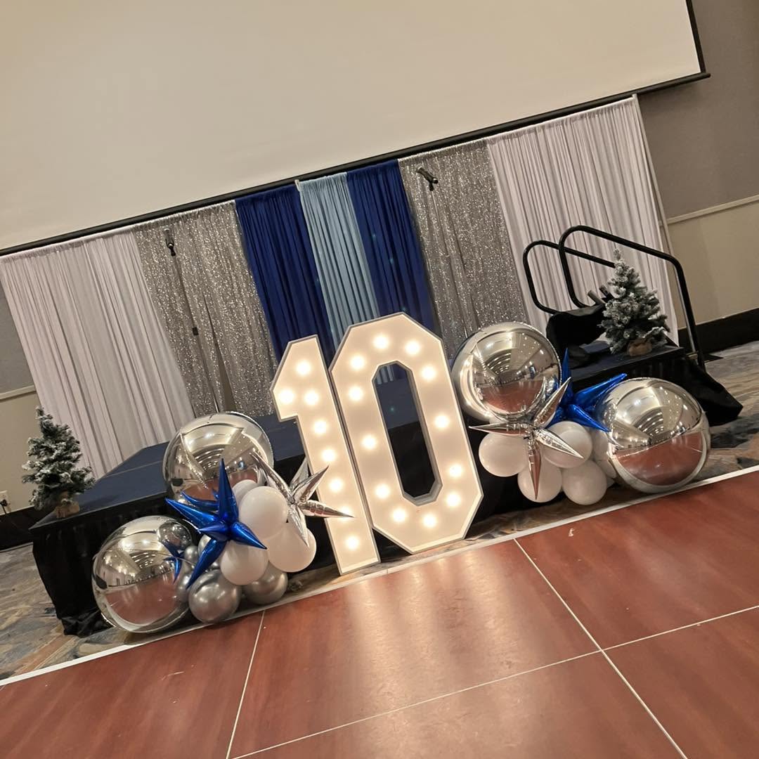 Marquee number 10 with chrome orbs, starbursts and navy and silver balloon clusters