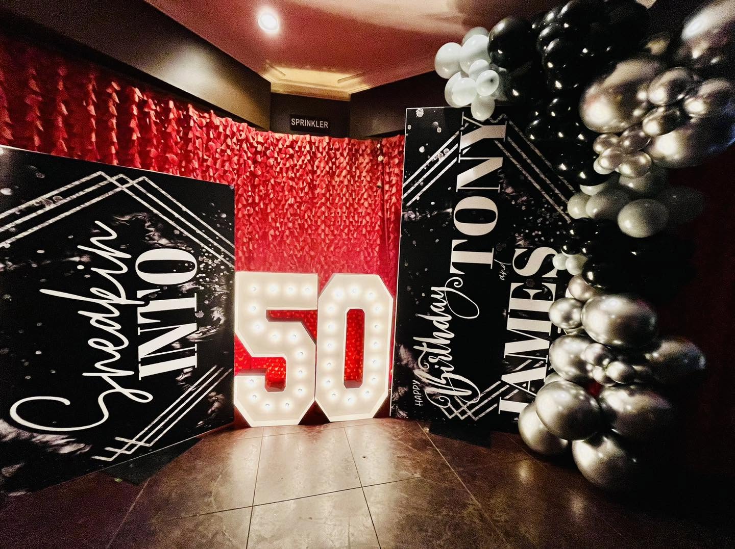 Birthday photo board display with marquee numbers and balloon garland