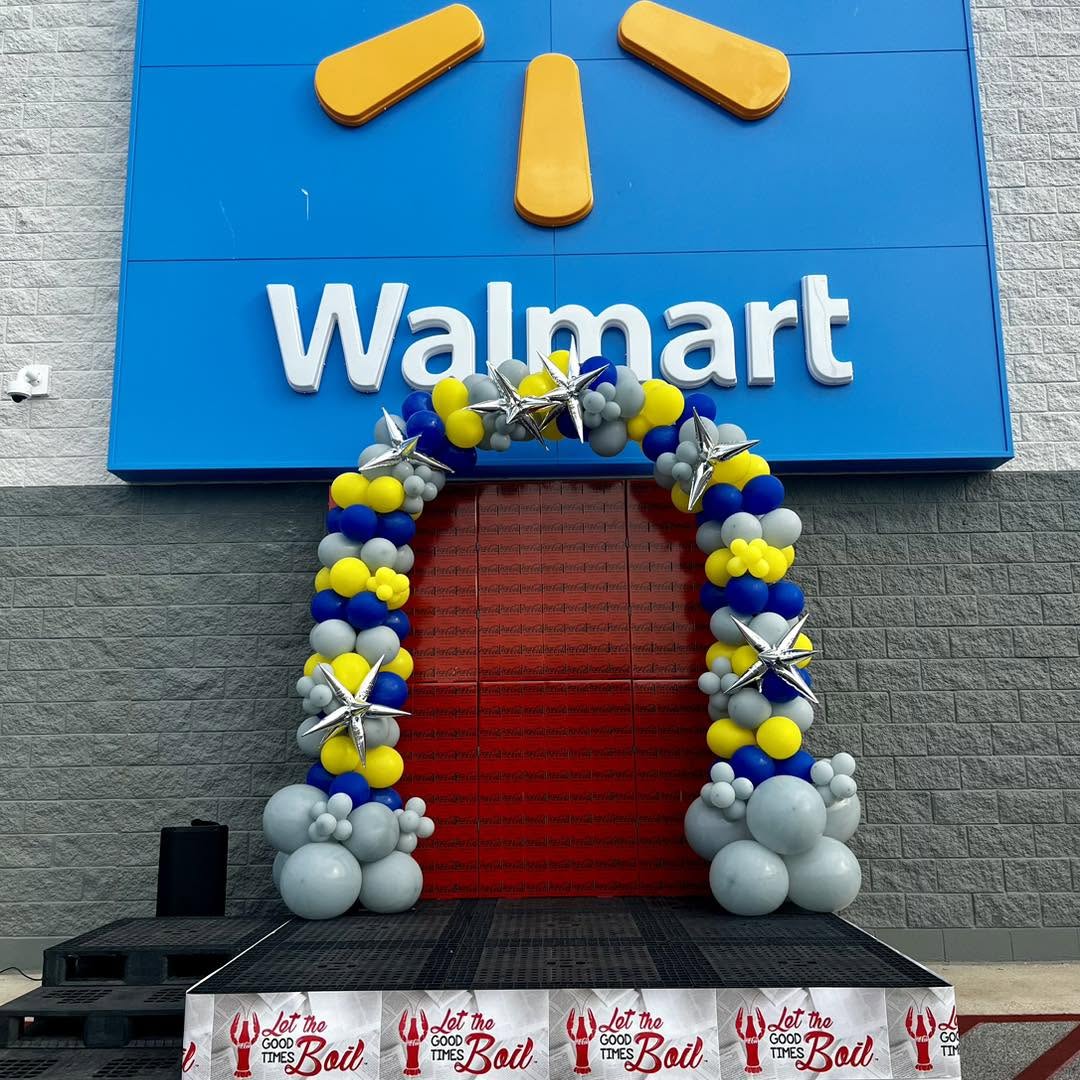Blue, yellow and grey balloon arch with silver starbursts at a Walmart entrance