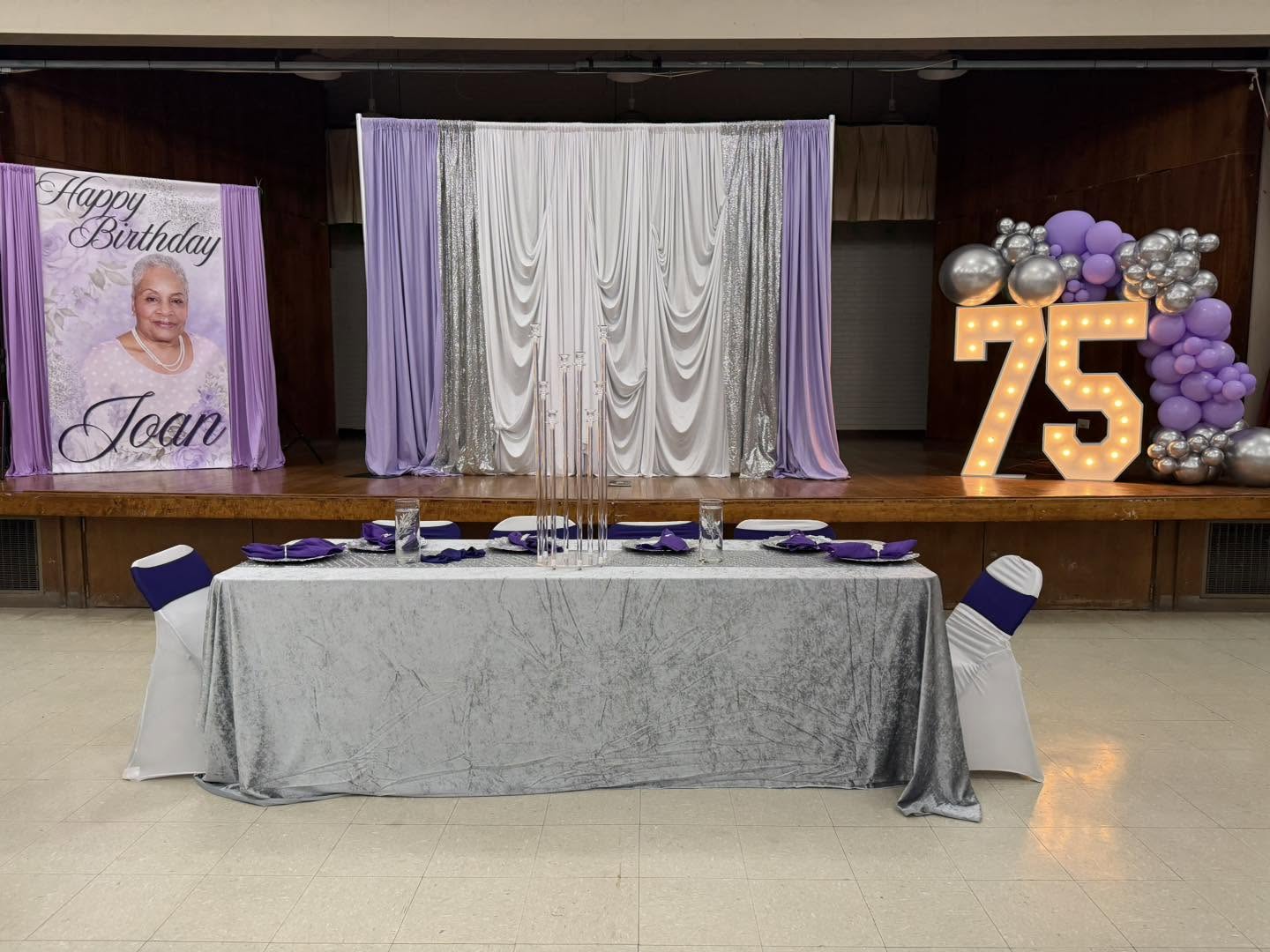 Lavender, silver and white draped stage backdrop with marquee numbers