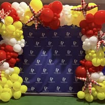 Red, yellow and white balloon columns framing a branded step-and-repeat