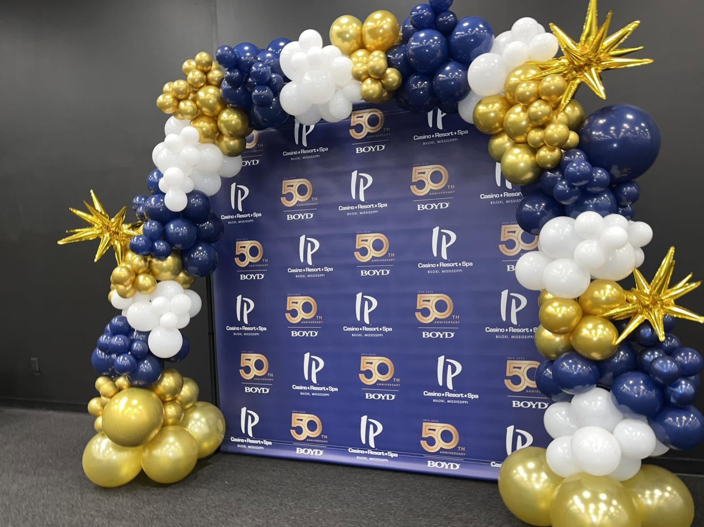 Navy and gold balloon arch framing a branded 50th anniversary step-and-repeat backdrop
